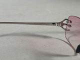sunglasses with a pink lens and a silver handle on a white surface