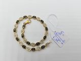 a gold bracelet with black and white stones on a white background