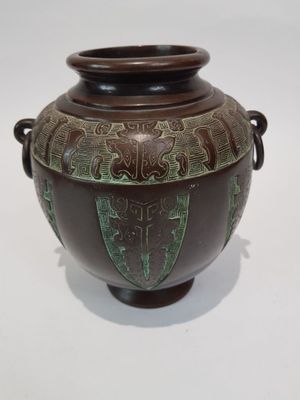 a brown vase with green designs on it on a white surface