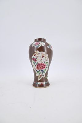 un vase marron orné de fleurs, posé sur un fond blanc