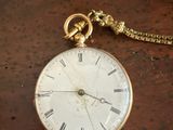 une montre de poche posée sur une table, avec une chaîne autour