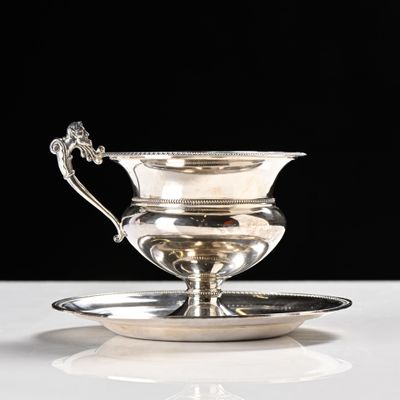 an antique silver plate with a saucer on it on a white surface