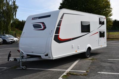 un petit camping-car blanc garé sur un parking
