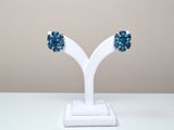 une paire de boucles d'oreilles en cristal bleu posées sur un présentoir blanc, sur une table blanche