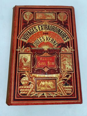 an old book on a white surface with a red cover and gold lettering