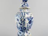 a blue and white vase with a bird on top of it