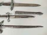 three old swords are displayed on a white surface