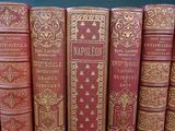 several old books are lined up in a row on a table