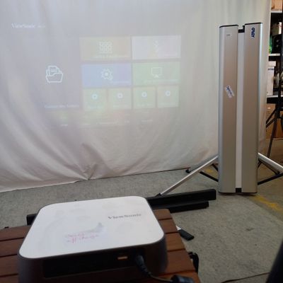 un projecteur posé sur une table devant un écran de projection