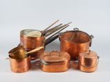 plusieurs casseroles et poêles de couleur cuivrée empilées les unes sur les autres