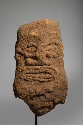 a stone head on a stand with a gray background