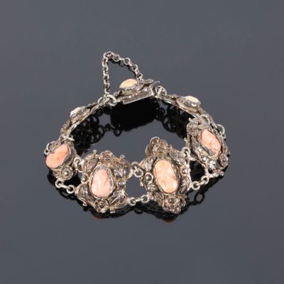a silver bracelet with pink stones on a black surface