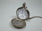 a silver pocket watch with a chain around it