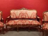 three chairs and a couch in a room with a red wall