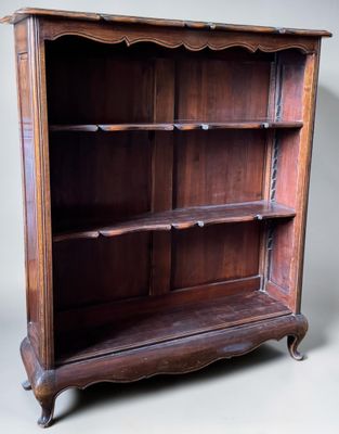 an old wooden bookcase with three shelves on wheels on a gray background