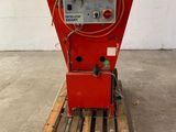 une machine rouge posée sur une palette dans un entrepôt