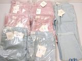 several pairs of jeans are sitting on a table in plastic bags