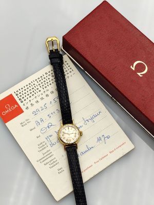 a watch sitting on top of a piece of paper next to a red box