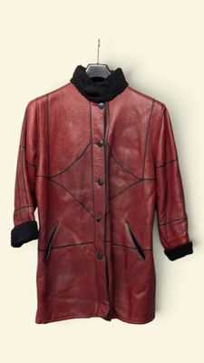 une veste en cuir suspendue à un cintre sur un mur blanc