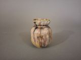 un petit vase posé sur une table, sur fond gris