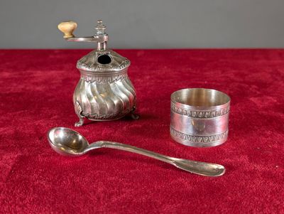 une cuillère en argent et une théière en argent posées sur une nappe rouge