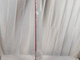 un vase en verre avec une anse rouge posé sur une table blanche