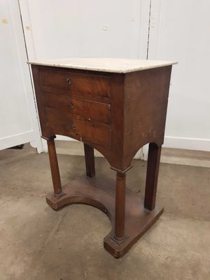 une vieille table en bois avec un plateau en marbre, posée sur un sol en ciment