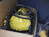 une boîte contenant un aspirateur jaune et un tuyau noir