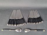 Plusieurs fourchettes et cuillères sont disposées en rangée sur une table