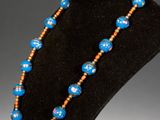 a necklace with blue and orange beads on a black mannequin