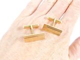 two pairs of gold cufflinks on a person ' s hand