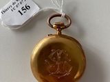 a gold pocket watch on a white table with a price tag