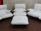 three white reclining chairs and a ottoman in a room with a wallpapered wall