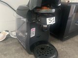 a coffee maker sitting on the floor next to a microwave