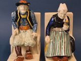 pair of ceramic figurines of two people sitting on a bench