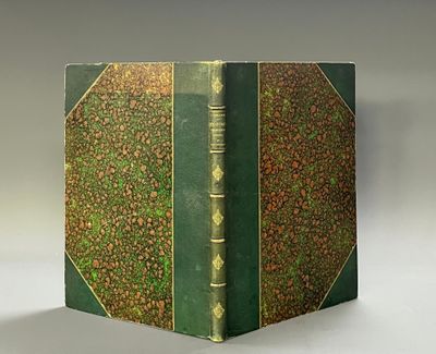 an old book with a green cover sitting on top of a white table