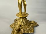 a gold figurine of a man standing on top of a pedestal