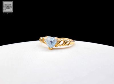 un gros plan d'une bague en or sertie d'une topaze bleue en forme de cœur