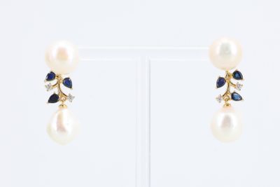 paire de boucles d'oreilles ornées de perles et de saphirs sur un support