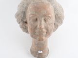une sculpture représentant une tête de femme sur un mur blanc