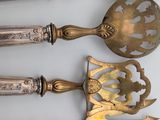 four pieces of silverware with ornate designs on them sitting on a table