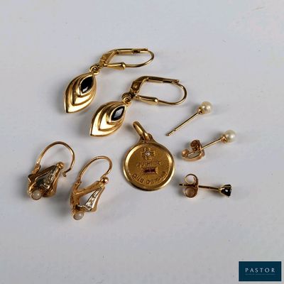 plusieurs paires de boucles d'oreilles en or et une montre en or posées sur une surface blanche