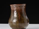 a brown vase sitting on a table with a black background
