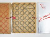 Plusieurs livres sont alignés sur une surface blanche, avec un ruban rouge
