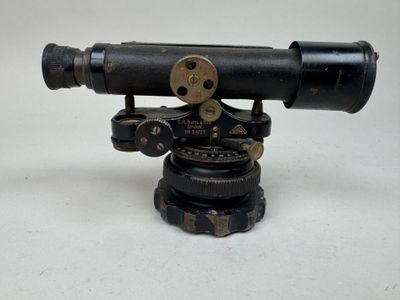 un vieux télescope posé sur un trépied, sur une surface blanche