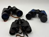 three pairs of binoculars sitting on top of a white surface