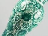 an image of a green and white vase with flowers on it