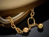 gold plated bracelet with bells and a hat on a black surface