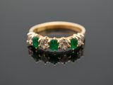 un gros plan d'une bague en or sertie de pierres vertes sur un fond noir