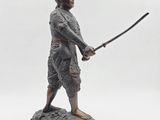 a statue of a man holding a sword on top of a rock